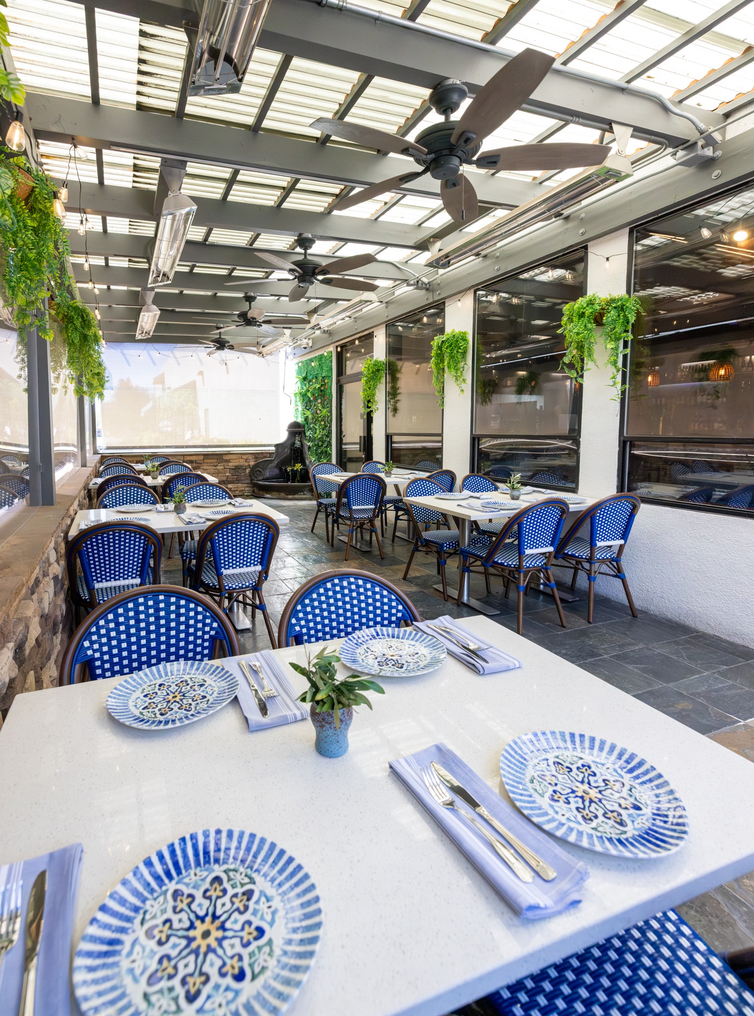 Patio table setting with blue-and-white plates and olive branch centerpiece