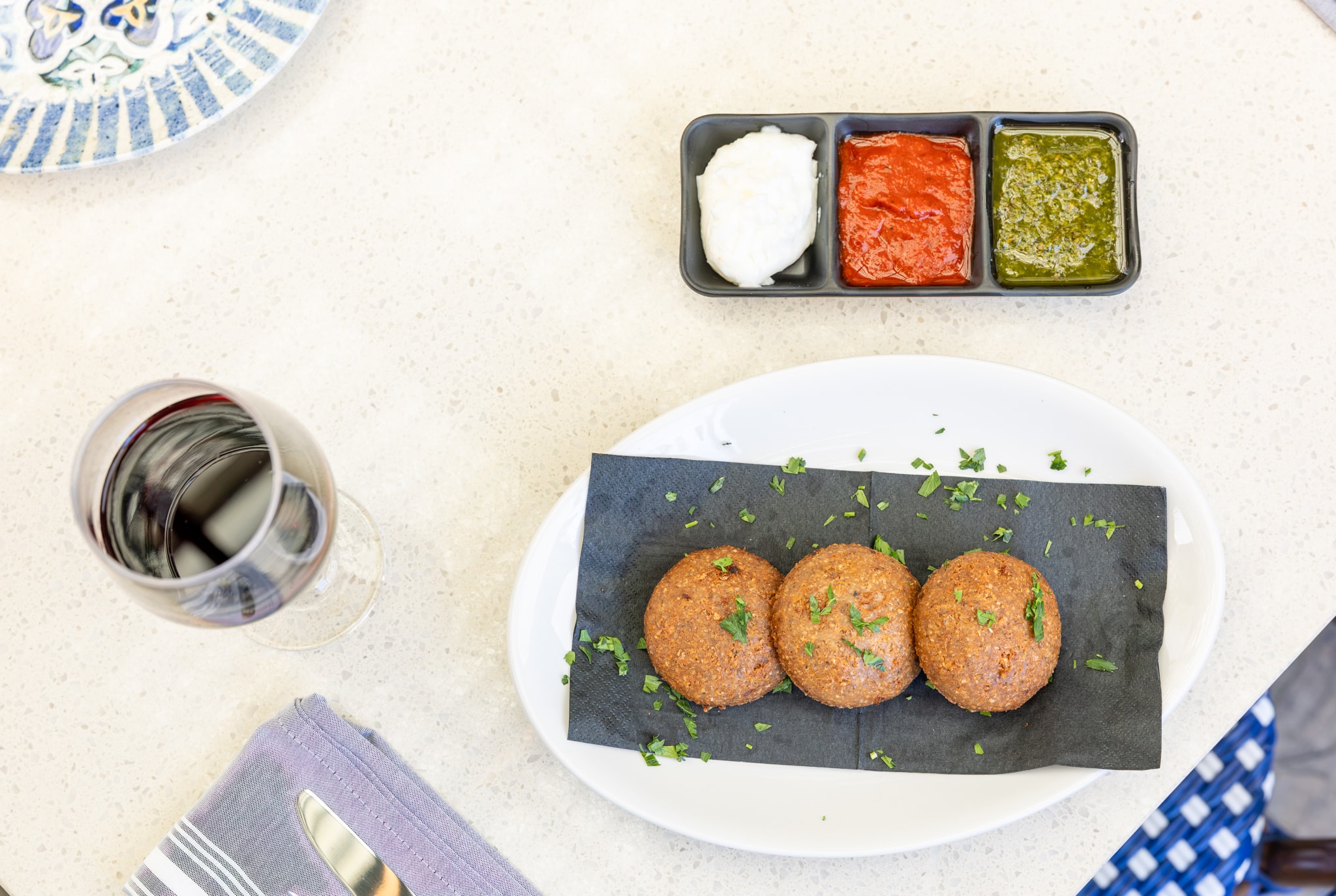 Fried kebbeh trio with three dipping sauces and a glass of red wine